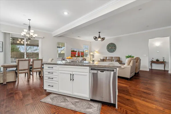 a kitchen with a sink dishwasher a dining table and chairs with wooden floor