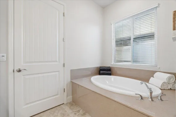 a bathroom with a granite countertop bathtub and window