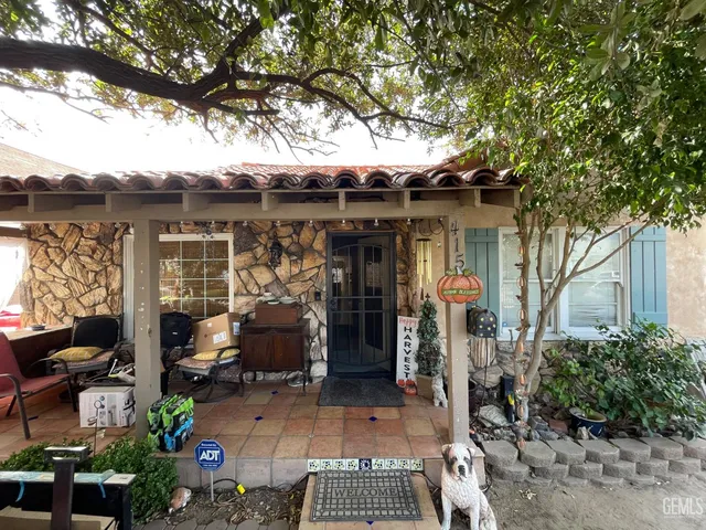a view of a patio with table and chairs potted plants and large tree