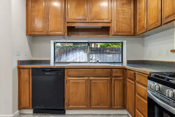 a kitchen with granite countertop wooden cabinets and a stove top oven