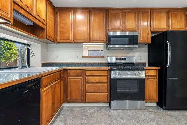 a kitchen with stainless steel appliances granite countertop wooden cabinets a stove top oven a granite counter tops and a window