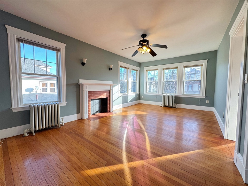 a view of empty room with wooden floor and fan