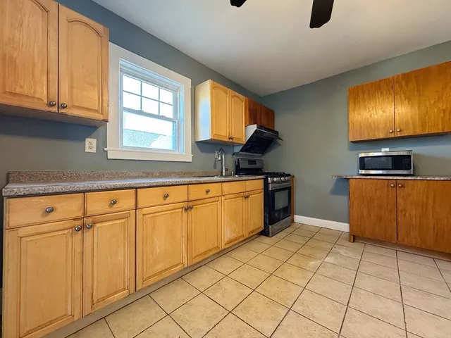 a kitchen with stainless steel appliances granite countertop a stove a sink and a microwave