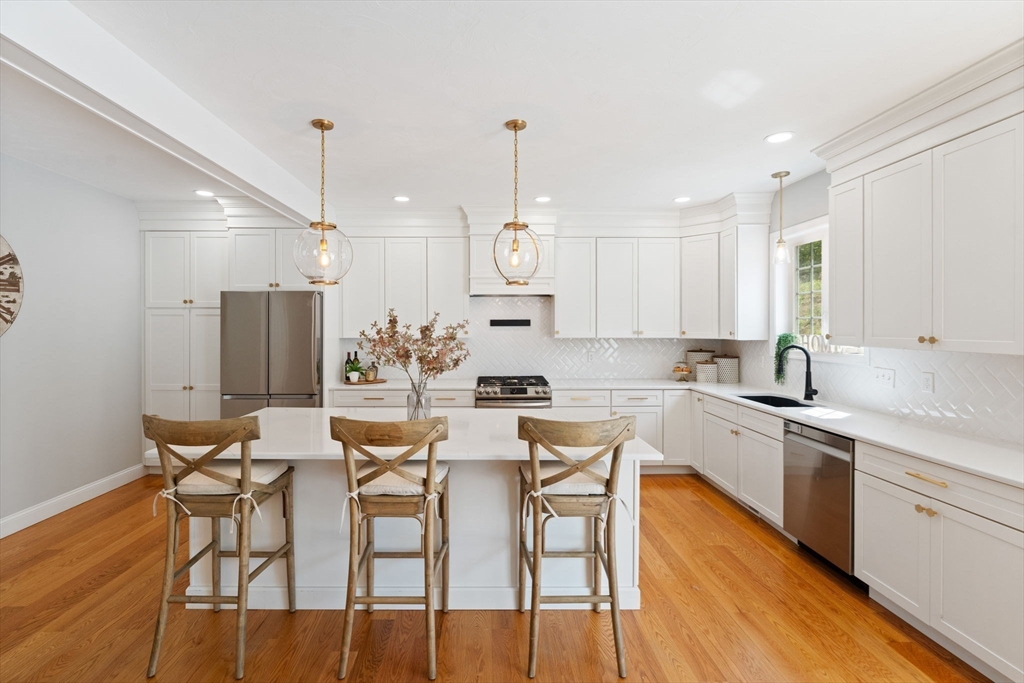 11 Chadwick Road Hudson, MA 01749 - Photo 16 of 39 a kitchen with stainless steel appliances kitchen island granite countertop a dining table chairs and white cabinets