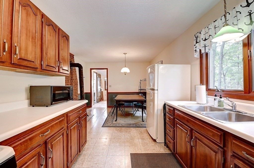 20 Old Acres Road Holland, MA 01521 - Photo 5 of 36 a kitchen with stainless steel appliances kitchen island granite countertop a refrigerator a stove top oven a sink dishwasher and wooden cabinets with wooden floor