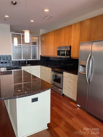 a kitchen with stainless steel appliances granite countertop a sink a stove and a refrigerator