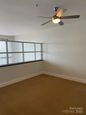 an empty room with a ceiling fan and windows