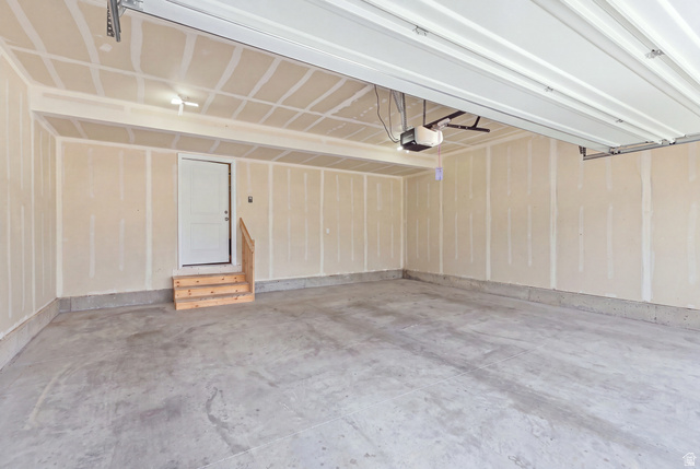 28 East Ginger Gold Road Santaquin, UT 84655 - Photo 36 of 36 Attached two-car garage with a concrete floor, an overhead door, and an internal access door with a wooden stair landing