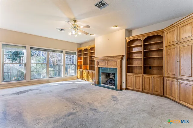 an empty room with windows and fireplace