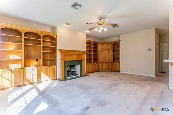 an empty room with windows and chandelier fan