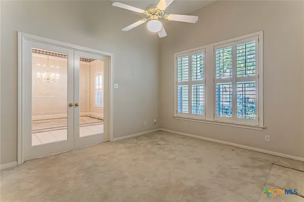 an empty room with windows and fan