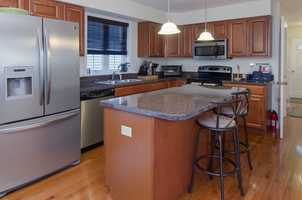2 Sterling Lane, Unit 2 Walpole, MA 02081 - Photo 2 of 27 a kitchen with stainless steel appliances granite countertop a sink a stove a refrigerator cabinets and a dining table