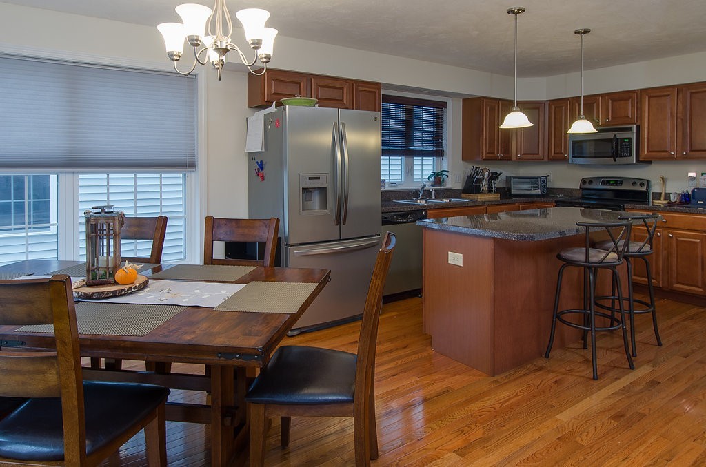2 Sterling Lane, Unit 2 Walpole, MA 02081 - Photo 6 of 27 a kitchen with stainless steel appliances granite countertop a refrigerator a stove a sink a dining table and chairs with wooden floor