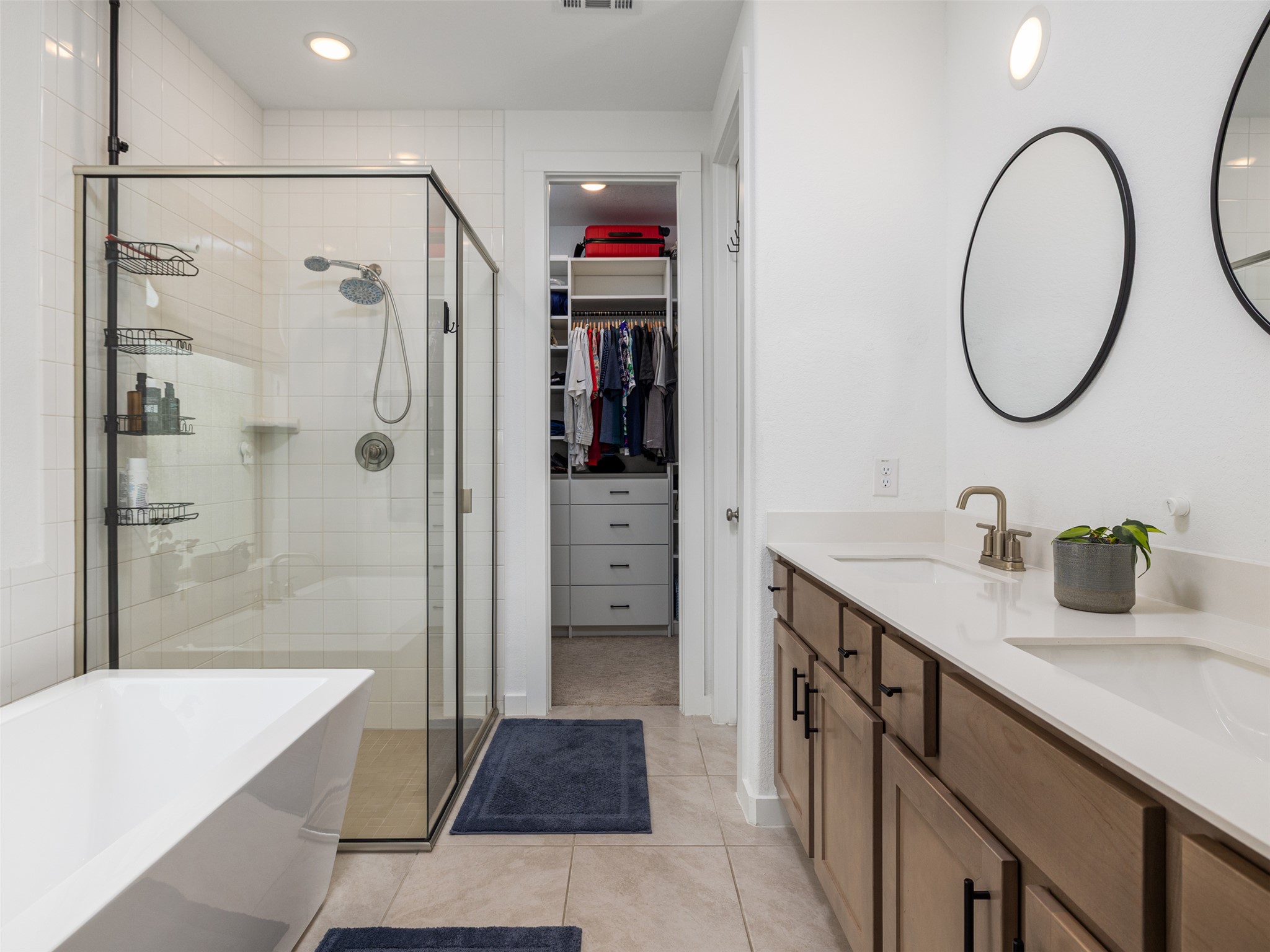 233 Arrowhead Mound Road Georgetown, TX 78628 - Photo 11 of 40 Bathroom featuring a freestanding tub, a shower stall, double vanity, light tile patterned floors, and a walk in closet