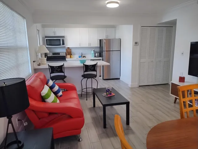 a living room with furniture a flat screen tv and a refrigerator