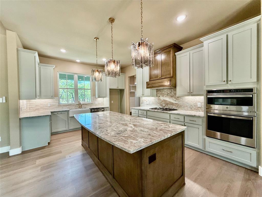 114 Ridgeline Drive Chico, TX 76431 - Photo 5 of 23 a kitchen with kitchen island granite countertop wooden cabinets and a granite counter tops