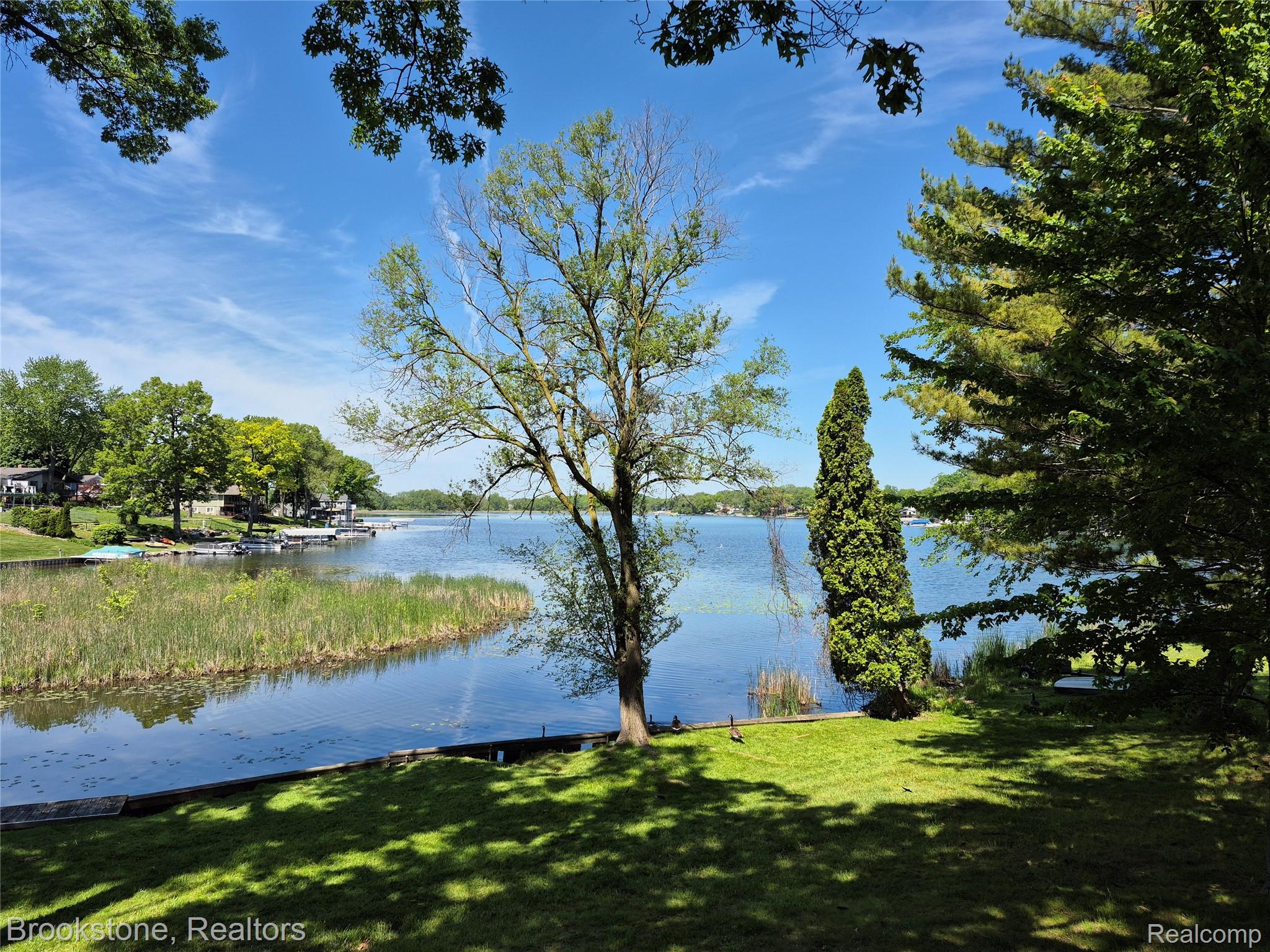 4295 Sashabaw Road Waterford, MI 48329 - Photo 4 of 37 Expansive waterfront property featuring a manicured lawn, mature trees, and direct water access