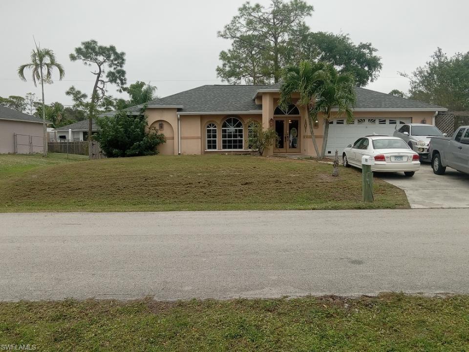 8213 Albatross Road Fort Myers, FL 33967 - Photo 2 of 17 a view of a white house next to a yard and a large tree