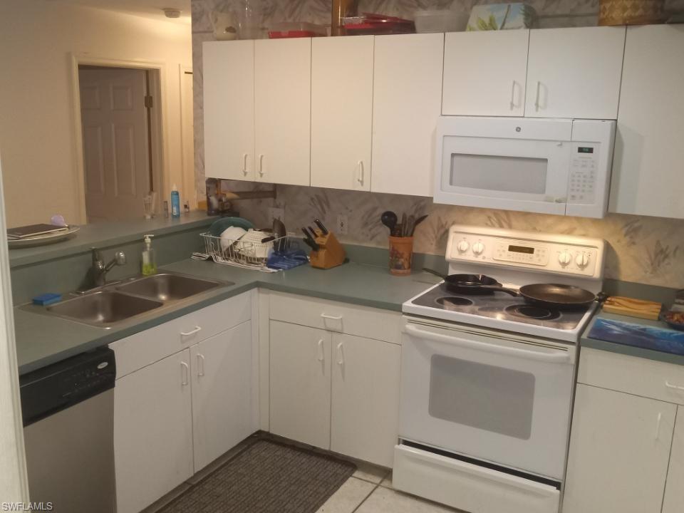 8213 Albatross Road Fort Myers, FL 33967 - Photo 7 of 17 a kitchen with white cabinets and appliances