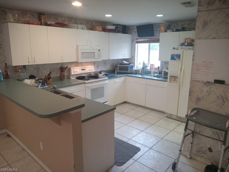 8213 Albatross Road Fort Myers, FL 33967 - Photo 9 of 17 a kitchen with a sink a refrigerator and cabinets