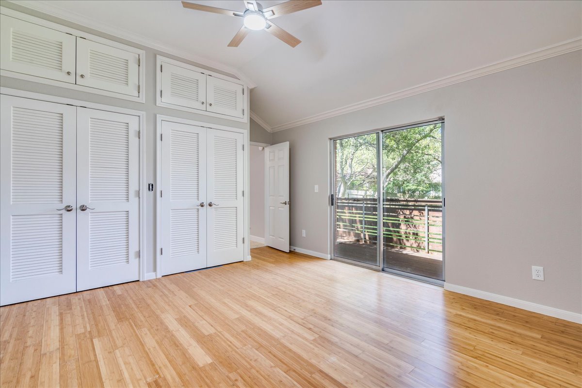 6530 Needham Lane Austin, TX 78739 - Photo 15 of 29 Sliding doors invite outdoor views, complementing the natural wood flooring and ample closet storage in this inviting bedroom.