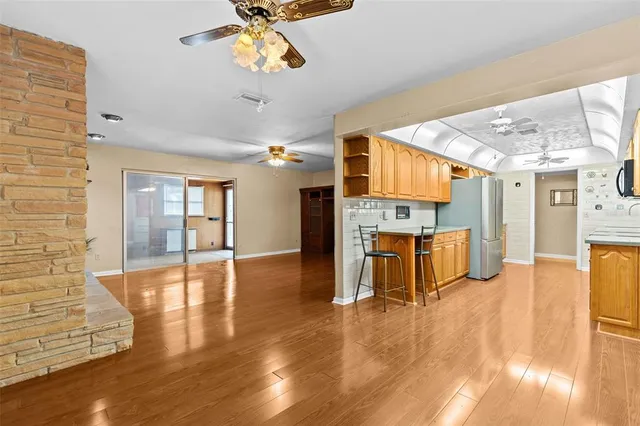 a view of an empty room with wooden floor fireplace and a window
