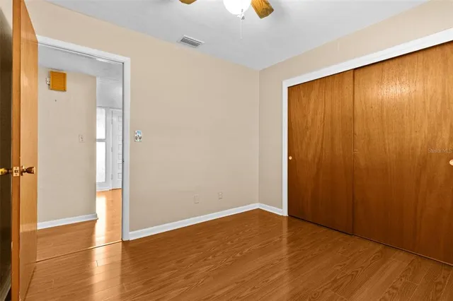 an empty room with wooden floor fan and windows