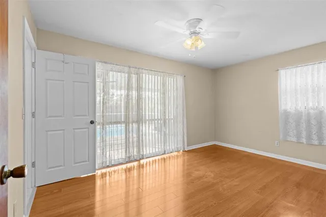 a view of an empty room with window and wooden floor