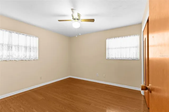 a view of an empty room with window and wooden floor