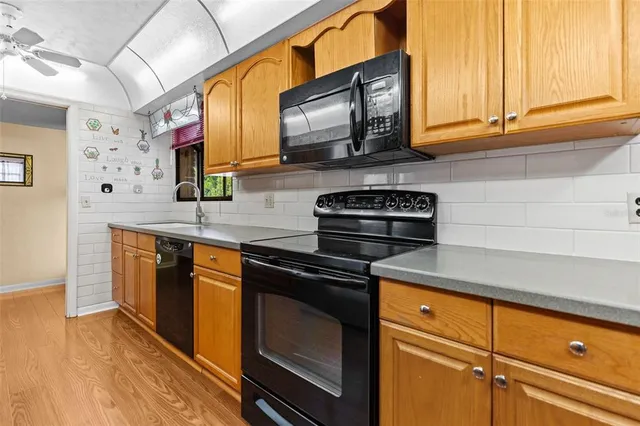 a kitchen with granite countertop wooden floors white cabinets and stainless steel appliances