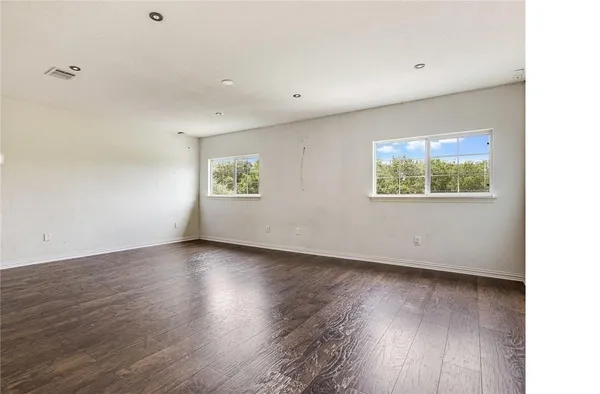 an empty room with wooden floor and windows