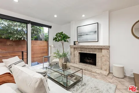 a living room with furniture a fireplace and a floor to ceiling window