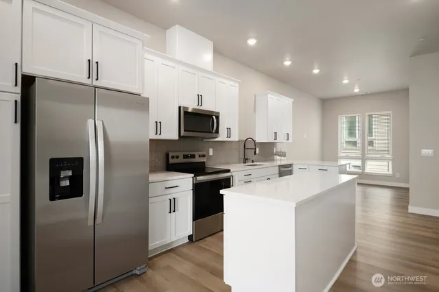 a kitchen with a sink a center island stainless steel appliances and cabinets