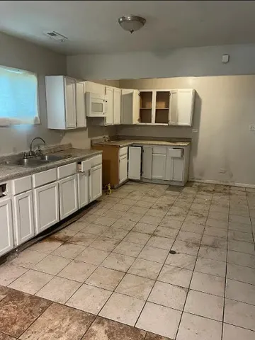 a large white kitchen with kitchen island granite countertop a black white checkered floor