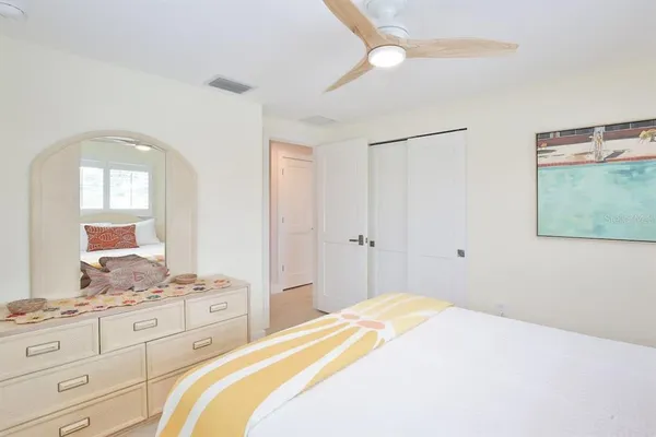 a large bed sitting in a bedroom next to a window with a large mirror and dresser