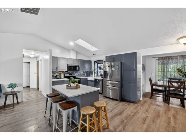a kitchen with a dining table chairs refrigerator and microwave