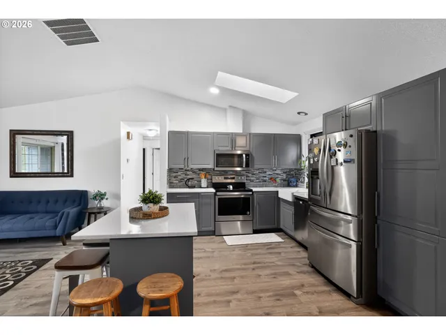 a kitchen with stainless steel appliances granite countertop a refrigerator a sink dishwasher a stove with wooden cabinets