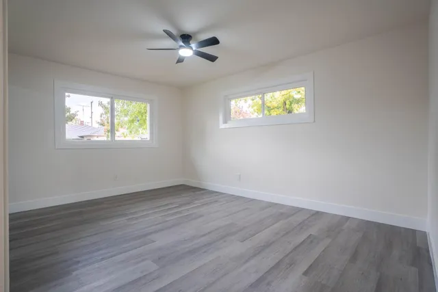 a view of an empty room with wooden floor and a window