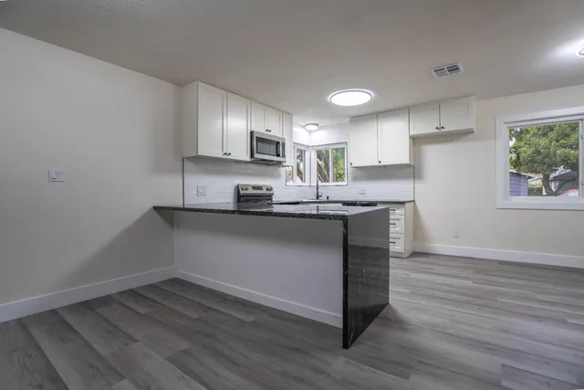 a kitchen with kitchen island granite countertop a sink cabinets and stainless steel appliances