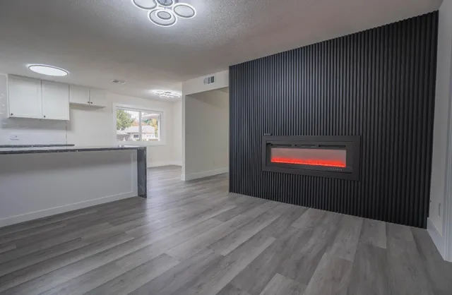 a view of kitchen and empty room with wooden floor