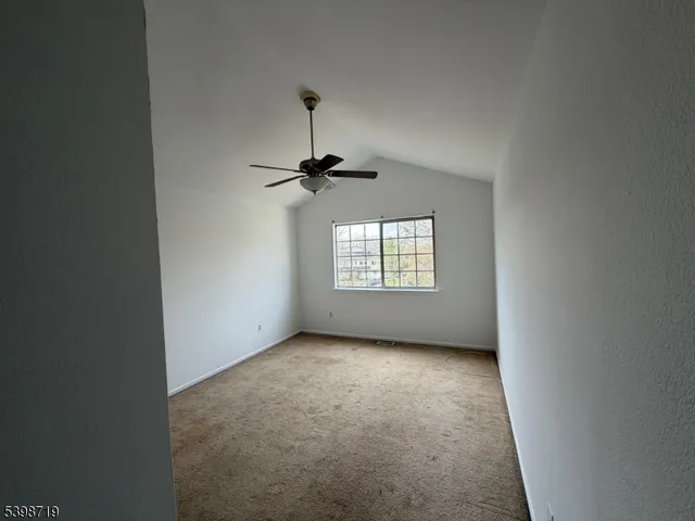 en empty room with windows and chandelier fan