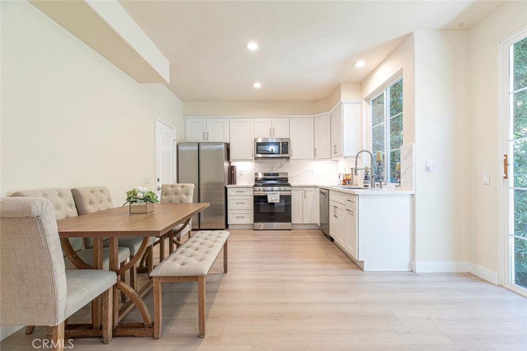 23301 Montecito Place Valencia, CA 91354 - Photo 12 of 45 a kitchen with a table chairs a sink dishwasher a refrigerator and cabinets with wooden floor