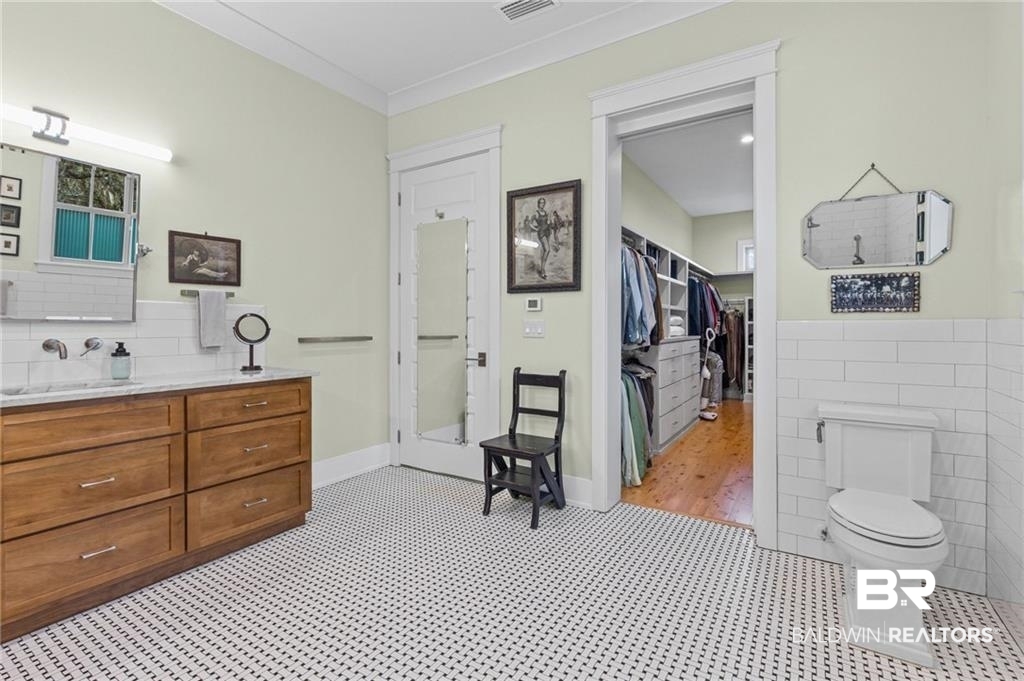 2730 Gator Road Mobile, AL 36605 - Photo 18 of 42 Full bathroom featuring tile walls, vanity, a wainscoted wall, a spacious closet, and crown molding