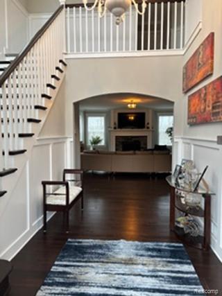 2500 Walnut View Drive Howell, MI 48855 - Photo 5 of 41 Foyer entrance with a decorative wall, a wainscoted wall, stairway, dark wood-style floors, and a fireplace