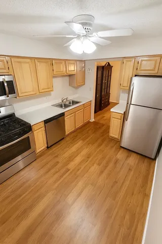 a view of kitchen with stainless steel appliances wooden floor and large window