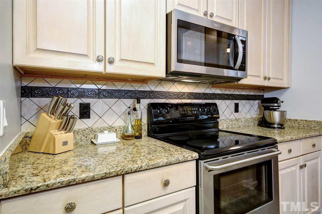 12305 Amoretto Way Raleigh, NC 27613 - Photo 7 of 30 Large breakfast bar is great for gathering all your family together and catching up on the day. Gorgeous back splash and vinyl tile flooring in the kitchen and baths.