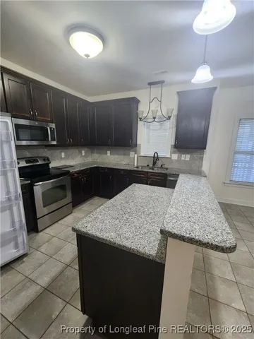 a kitchen with stainless steel appliances granite countertop a sink a stove a microwave and cabinets