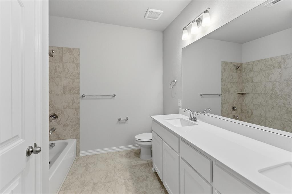 1329 Frio Drive Springtown, TX 76082 - Photo 12 of 25 Bathroom featuring a double vanity with white cabinetry and integrated sinks, a full-width mirror, and a bathtub with tiled surround