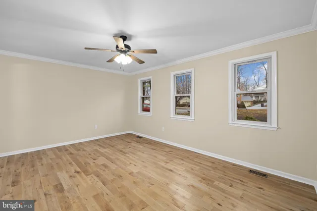 a view of an empty room with window and wooden floor