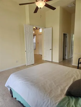 a spacious bedroom with a bed closet and chandelier